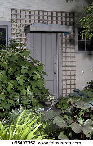 Stock Image - PATIO DETAIL: doorway to garage, lattice surrounds shade plants,. Fotosearch