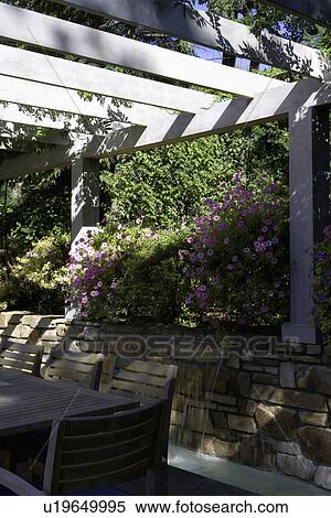Stock Photography - PATIO: pergola over dining area, waterfall behind, close up. Fotosearch