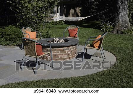 PATIOS: brick fire pit surrounded by four chairs with colorful pillows,, hammock View Large Photo Image Stock Photo - PATIOS: brick fire pit surrounded by four chairs with colorful pillows,, hammock. Fotosearch