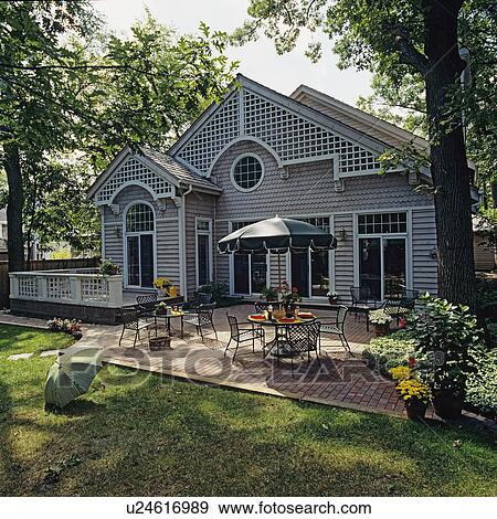 PATIOS: Brick patio, umbrella over dining area, raised deck to left, contemporary home with lattice and fish scale siding, transom windows View Large Photo Image Stock Photo - PATIOS: Brick patio, umbrella over dining area, raised deck to left, contemporary home with lattice and fish scale siding, transom windows. Fotosearch