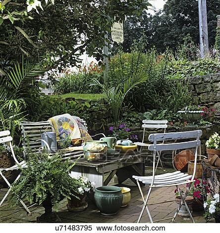 PATIOS: Eclectic styled area, weathered white patio furniture, assorted vintage flower pots, brick patio, straw baskets, potted Boston fern, palms. Jail House Antiques Mineral point View Large Photo Image Stock Photography - PATIOS: Eclectic styled area, weathered white patio furniture, assorted vintage flower pots, brick patio, straw baskets, potted Boston fern, palms. Jail House Antiques Mineral point. Fotosearch