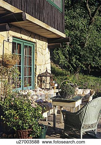 Stock Photo - PATIOS: Seating area on stone patio with wicker furniture, floral cushions, French Country feel. Potted rose bush.. Fotosearch