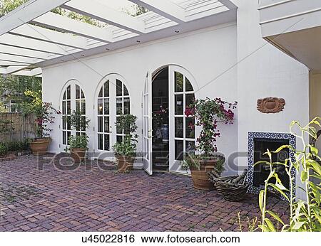 PATIOS: View of red brick floor patio off living room w/ fireplace, white stucco walls, potted plants. View Large Photo Image Stock Photograph - PATIOS: View of red brick floor patio off living room w/ fireplace, white stucco walls, potted plants.. Fotosearch