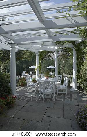 PERGOLAS: Classical white columned pergola, grey slate patio, Chinese Chippendale style patio set, more patio and beams showing looking to pool area from above dining area, two patio umbrellas in distance View Large Photo Image Stock Image - PERGOLAS: Classical white columned pergola, grey slate patio, Chinese Chippendale style patio set, more patio and beams showing looking to pool area from above dining area, two patio umbrellas in distance. Fotosearch
