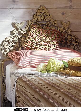 PILLOWS: Pillows on twin bed with ornate antique iron headboard. Pink, green, and white colors. Staw hat also View Large Photo Image Stock Image - PILLOWS: Pillows on twin bed with ornate antique iron headboard. Pink, green, and white colors. Staw hat also . Fotosearch