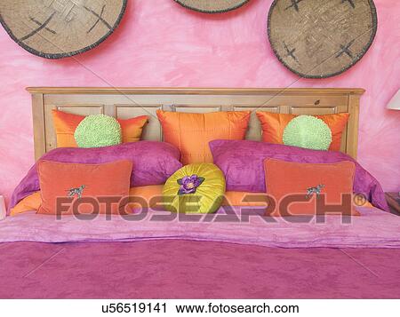 Stock Image - Pink and orange throw pillows on bed; Tannersville; New York; USA. Fotosearch