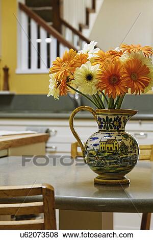 Stock Photo - Pitcher of Gerber Daisies on Kitchen table. Fotosearch