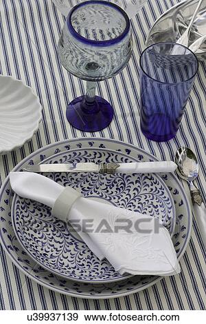 PLACE SETTINGS: casual blue and white place setting, blue glassware, patterned blue plates, white napkin, striped ticking, outdoor dining View Large Photo Image Stock Photo - PLACE SETTINGS: casual blue and white place setting, blue glassware, patterned blue plates, white napkin, striped ticking, outdoor dining. Fotosearch