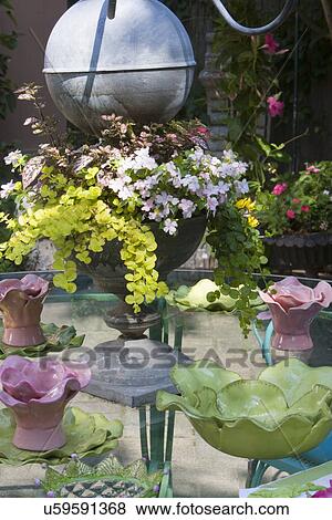 Stock Photo - PLACE SETTINGS: cottage chic style place settings, zinc candelabra with a place for potted flowers, pink and green pottery on a glass top table outside. Fotosearch