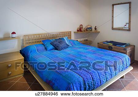 Stock Photograph - Platform bed with blue comforter; Italy. Fotosearch