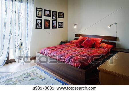 Stock Photography - Platform bed with red comforter; Italy. Fotosearch