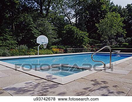 Stock Photo - Pools: Vertical 20' x 46' lap pool, deep end with diving board, retractable cover, Iowa limestone, elevated lawn and flower bed in background. Red Geraniums on left. . Fotosearch