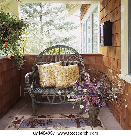 Stock Photo - PORCH: Bungalow porch, cedar shake, painted green twig bench with yellow floral patterned pillows, wildflowers in vintage basket,. Fotosearch