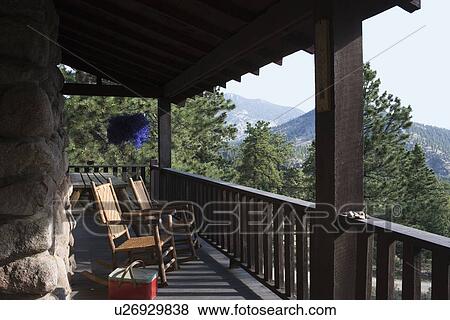 Stock Photo - PORCH: Scenic view of mountains, two twig rockers. picnic basket. Fotosearch