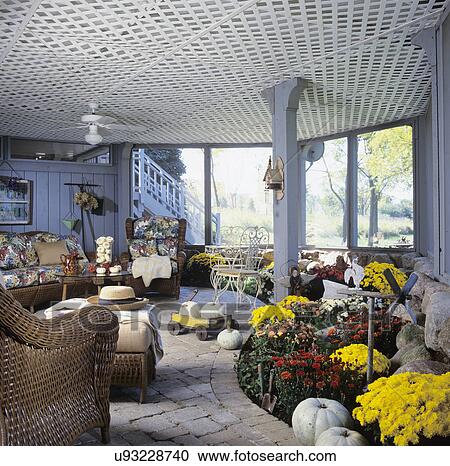 PORCH: screened porch, underneath deck, white pumpkins, floral cushioned wicker sofa and chairs to left with flower border underneath deck View Large Photo Image Stock Image - PORCH: screened porch, underneath deck, white pumpkins, floral cushioned wicker sofa and chairs to left with flower border underneath deck. Fotosearch