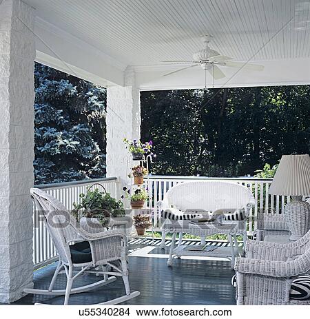 PORCH: White wainscot ceiling with fan, dark green painted floors, white wicker on front porch of a four square farmhouse in the suburbs, looking to wicker sofa, coffee table and two rockers, plant stand in corner View Large Photo Image Picture - PORCH: White wainscot ceiling with fan, dark green painted floors, white wicker on front porch of a four square farmhouse in the suburbs, looking to wicker sofa, coffee table and two rockers, plant stand in corner. Fotosearch
