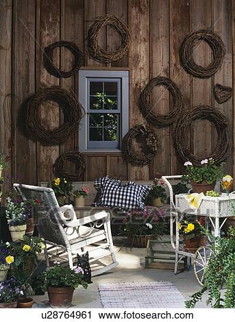 PORCHES: Country home, porch with twig wreaths on weathered wood wall, wicker rocker, potted flowers, small window, white wicker cart View Large Photo Image Stock Image - PORCHES: Country home, porch with twig wreaths on weathered wood wall, wicker rocker, potted flowers, small window, white wicker cart. Fotosearch