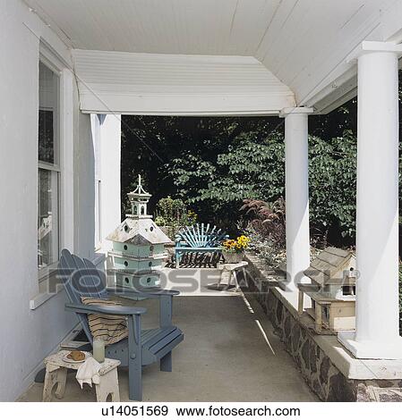 PORCHES: Styled simple, shabby chic porch, blue Adirondack chair, 2 large birdhouses, blue settee in background, white walls, ceiling, columns View Large Photo Image Stock Photo - PORCHES: Styled simple, shabby chic porch, blue Adirondack chair, 2 large birdhouses, blue settee in background, white walls, ceiling, columns . Fotosearch