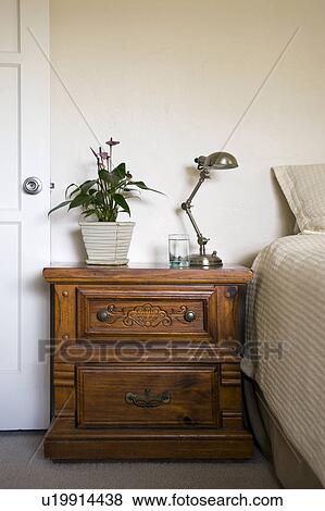 Stock Photo - Potted plant and lamp on nightstand beside bed, San Diego, California, United States of America. Fotosearch