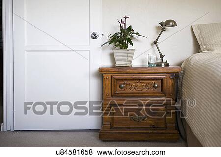 Stock Photo - Potted plant and on nightstand beside bed, San Diego, California, United States of America. Fotosearch