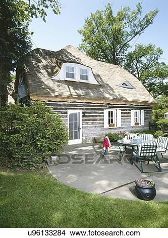 Picture - Rear exterior of log home with furniture in back patio. Fotosearch