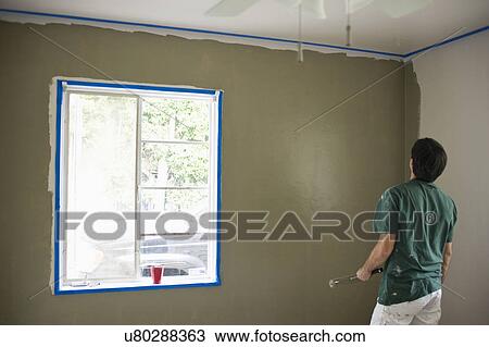 Rear view of a man painting wall View Large Photo Image Stock Image - Rear view of a man painting wall. Fotosearch