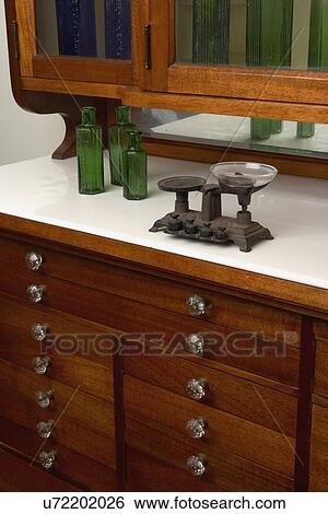 Scales Collection: Cast iron apothecary counter scale, 1 removable pan, circa 1890's, sitting on antique dental cabinet with green glass apothecary bottles. View Large Photo Image Stock Photograph - Scales Collection: Cast iron apothecary counter scale, 1 removable pan, circa 1890's, sitting on antique dental cabinet with green glass apothecary bottles.. Fotosearch