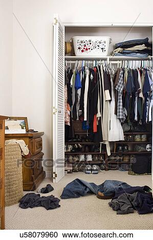 Stock Image - Scattered clothes outside cluttered closet, San Diego, California, United States of America. Fotosearch