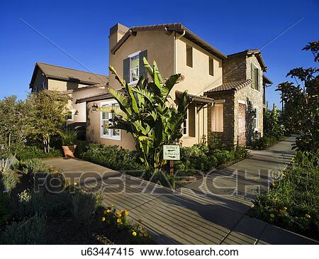 Stock Photography - Sidewalk and landscaping along contemporary Tuscan style home. Fotosearch