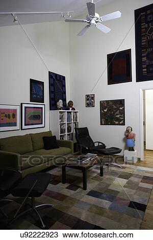 SITTING AREAS: Contemporary sitting area in a home library, folk art carvings, paintings and quilts, patchwork style area rug, olive colored sofa, black leather chairs, View Large Photo Image Stock Image - SITTING AREAS: Contemporary sitting area in a home library, folk art carvings, paintings and quilts, patchwork style area rug, olive colored sofa, black leather chairs,. Fotosearch