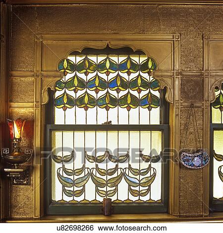 STAINED GLASS: Geometric design in windows, casing and wall painted gold, shades of green, blues, yellow on a frosted glass background. View Large Photo Image Stock Photograph - STAINED GLASS: Geometric design in windows, casing and wall painted gold, shades of green, blues, yellow on a frosted glass background. . Fotosearch