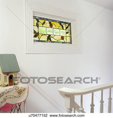 Stock Image - STAINED GLASS WINDOW - on wall of stairway. Birdhouse.. Fotosearch