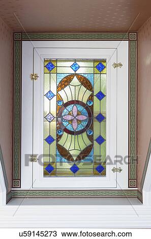 Stock Image - STAINED GLASS WINDOWS: Window, stained glass: Wallpaper border surrounds latched window, Aesthetic Movement style in green, blue, pink and magenta. Fotosearch