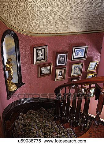 Stock Photography - stairway: William Morris runner, tone on tone wallpaper, turned balusters, winding staircase, faux finish woodwork, statuary niche. Fotosearch