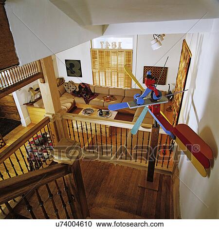 Stock Image - stairways: natural tone woods variety of colors, delicate spindles on banister, colorful whirligig on landing, stairs look out over living room space . Fotosearch