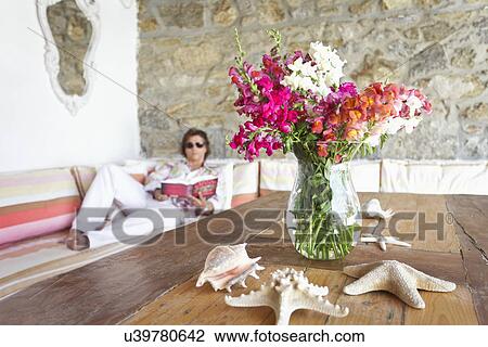Starfish and shells surrounding floral arrangement on wooden table with woman reading in background, Mykonos, Greece View Large Photo Image Stock Image - Starfish and shells surrounding floral arrangement on wooden table with woman reading in background, Mykonos, Greece. Fotosearch