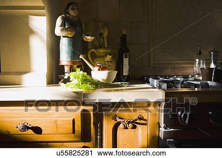 Stock Image - Statue and cooking supplies on kitchen counter. Fotosearch