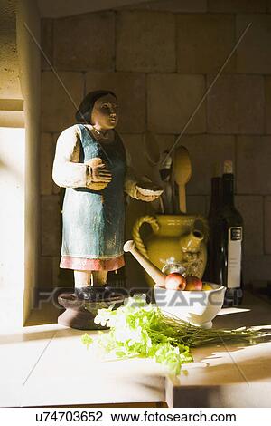 Stock Image - Statue and cooking supplies on kitchen counter. Fotosearch