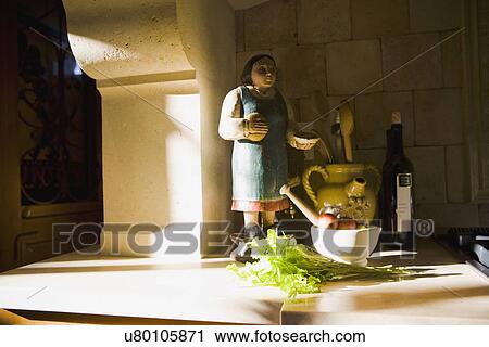 Stock Image - Statue and cooking supplies on kitchen counter. Fotosearch