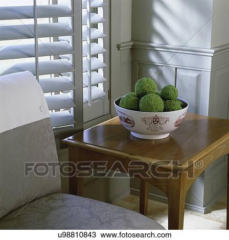 STILL LIFE: Bowl of hedge apples on table by upholstered chair in dining room, blind in background View Large Photo Image Stock Image - STILL LIFE: Bowl of hedge apples on table by upholstered chair in dining room, blind in background. Fotosearch