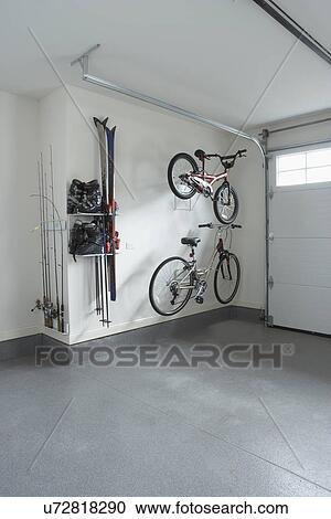 Stock Image - STORAGE: garage storage of sporting equipment, two bikes, ski boots and skis, fishing gear. Fotosearch