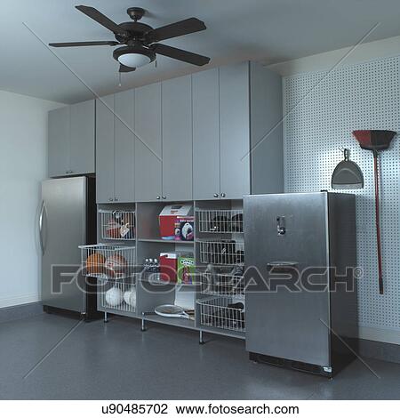 Stock Image - STORAGE: stainless steel refrigerator and beer kegger, wire pull out baskets with balls, shoes, sporting equipment, coolers, peg board, broom. Fotosearch
