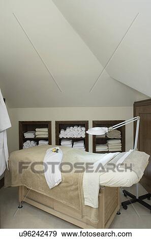Stores/Spa: Massage room: Clean neutral and white color scheme. Massage bed built into the wall, shelves hold rolls of white towels, lamp, white robe View Large Photo Image Stock Photo - Stores/Spa: Massage room: Clean neutral and white color scheme. Massage bed built into the wall, shelves hold rolls of white towels, lamp, white robe. Fotosearch