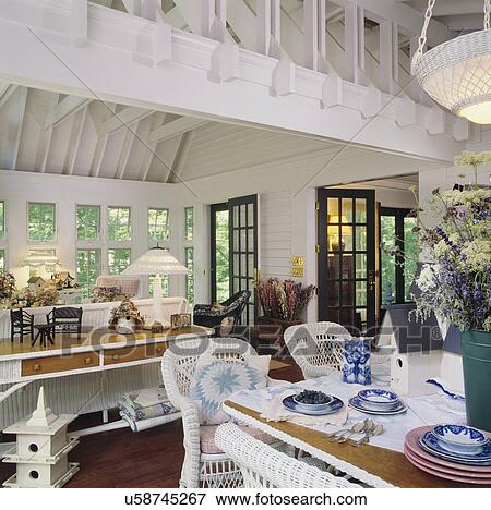 Stock Photo - SUN PORCH Family room, cottage country with white wicker, antique quilts and china, wildflower arrangements, summer retreat. Fotosearch