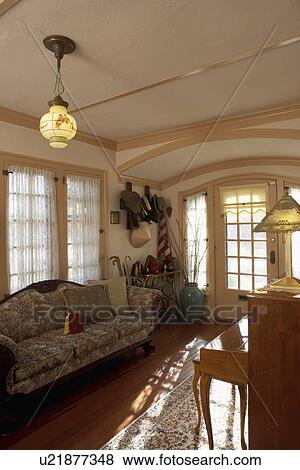 Stock Photo - SUNROOMS: Lace covered French doors and sidelights, vintage sofa, pendant lighting, hat rack, walking sticks by door, tall vase of pussy willows. Fotosearch