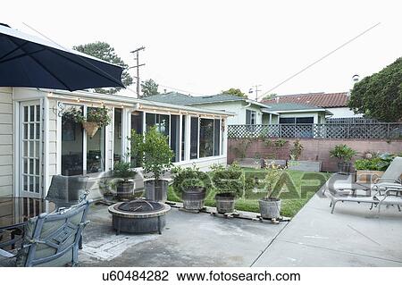 Stock Image - Sunshade and lounge chair at patio of house. Fotosearch