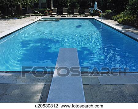 SWIMMING POOLS: Straight on view looking from over the diving board toward the four lounge chairs, basketball hoop, Iowa limestone View Large Photo Image Stock Image - SWIMMING POOLS: Straight on view looking from over the diving board toward the four lounge chairs, basketball hoop, Iowa limestone. Fotosearch