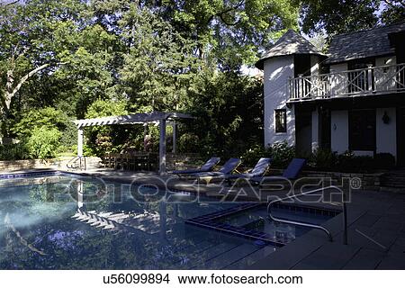 Picture - SWIMMING POOLS: white brick twp story French Normandy style pool house with porch and turret, four chaise lounges face pool, pergola covers a dining area. Fotosearch