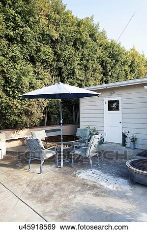 Table and chairs with sunshade on patio View Large Photo Image Stock Photo - Table and chairs with sunshade on patio. Fotosearch