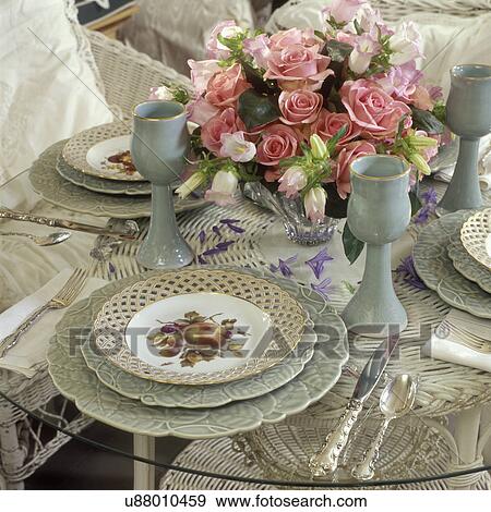 Stock Photo - TABLE SETTINGS: Wedgewood pale green plates and painted fruit plates, pottery goblets, glasses, pink rose arrangement, romantic, elegant cottage style. . Fotosearch